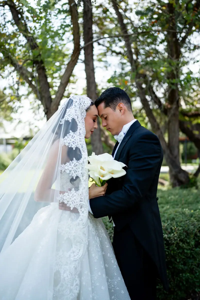 Novios frente con frente, ella con mantilla de encaje, en el jardín de La Folié Eventos